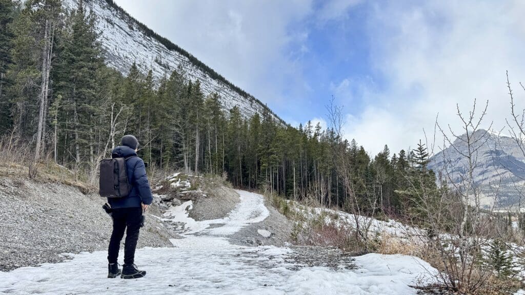 A scenic spot on mildly snow-covered Heart Creek Bunker Trail, one of the best hikes in Kananaskis, and about to walk to a pathway with trees on both sides