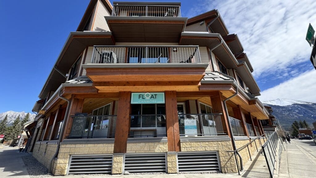 Street view of Float Canmore wellness spa, located in a rustic-chic building with mountain views and modern design, offering float therapy and relaxation services in downtown Canmore