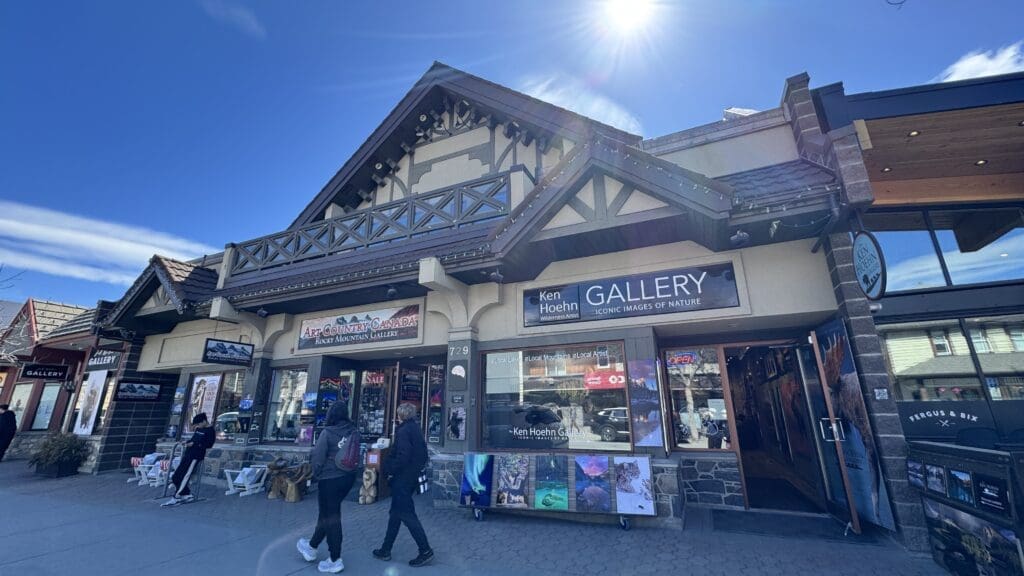 Street view of Art Country Canada and Ken Hoehn Gallery in Canmore, Alberta, showcasing local Canadian artwork, photography, and Rocky Mountain landscapes in a charming alpine-style building