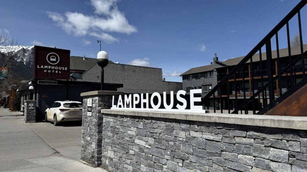 Exterior view of Lamphouse Hotel in downtown Canmore, Alberta, featuring modern alpine architecture with stone and wood finishes, nestled against the scenic backdrop of the Canadian Rockies.
