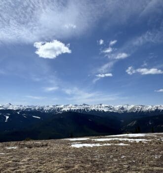 Panoramic view from Prairie Mountain summit in Kananaskis Alberta Canada showcasing snow capped peaks dense evergreen forests and wide open blue sky in the Canadian Rockies