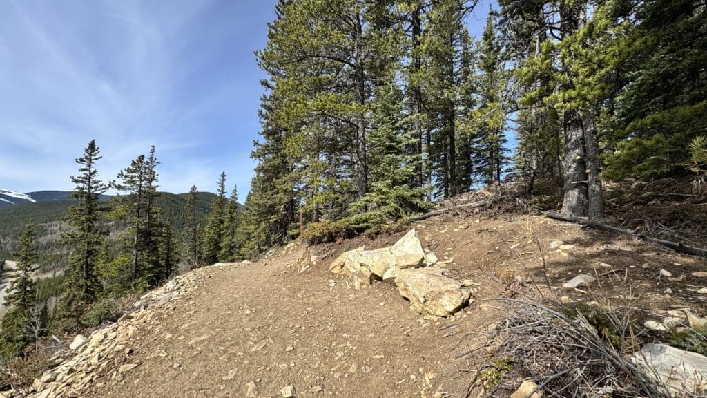 Scenic resting spot on Prairie Mountain Trail with rocky terrain and forest views overlooking pine-covered mountains